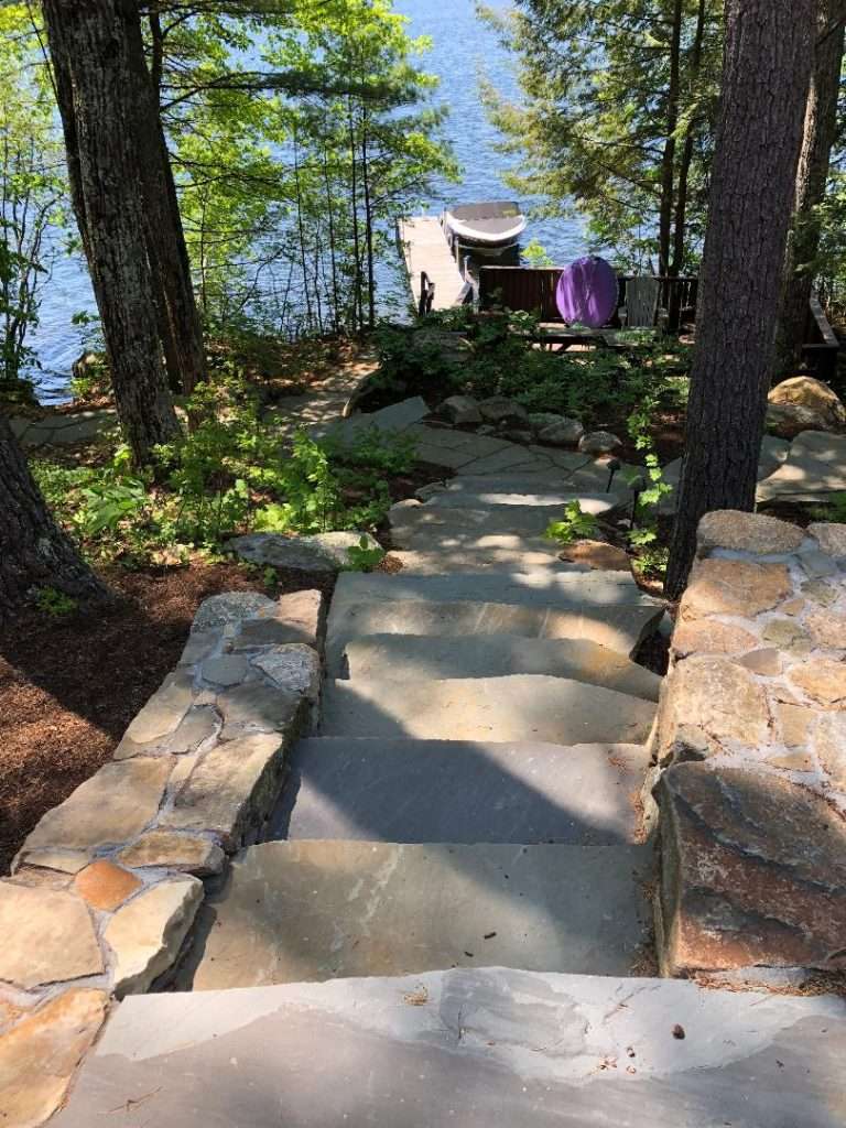 Lakefront granite steps and natural stone pathway leading to a waterfront dock by Landscapes by Tom in New Hampshire