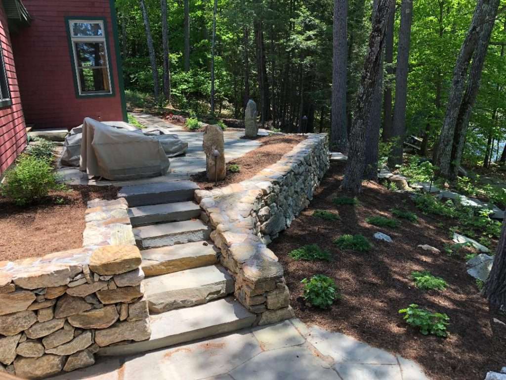 Natural stone terrace patio with retaining walls and custom granite steps by Landscapes by Tom in New Hampshire