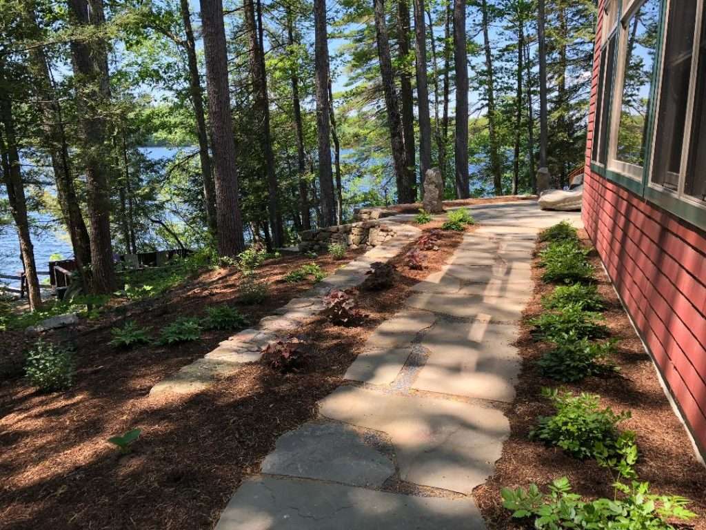 Lakefront natural stone walkway with woodland landscaping and garden beds by Landscapes by Tom in New Hampshire