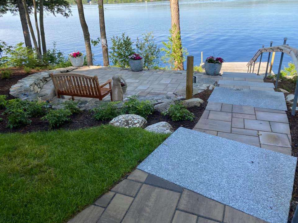 Lakefront paver patio with granite steps, seating area, and waterfront landscaping by Landscapes by Tom in New Hampshire