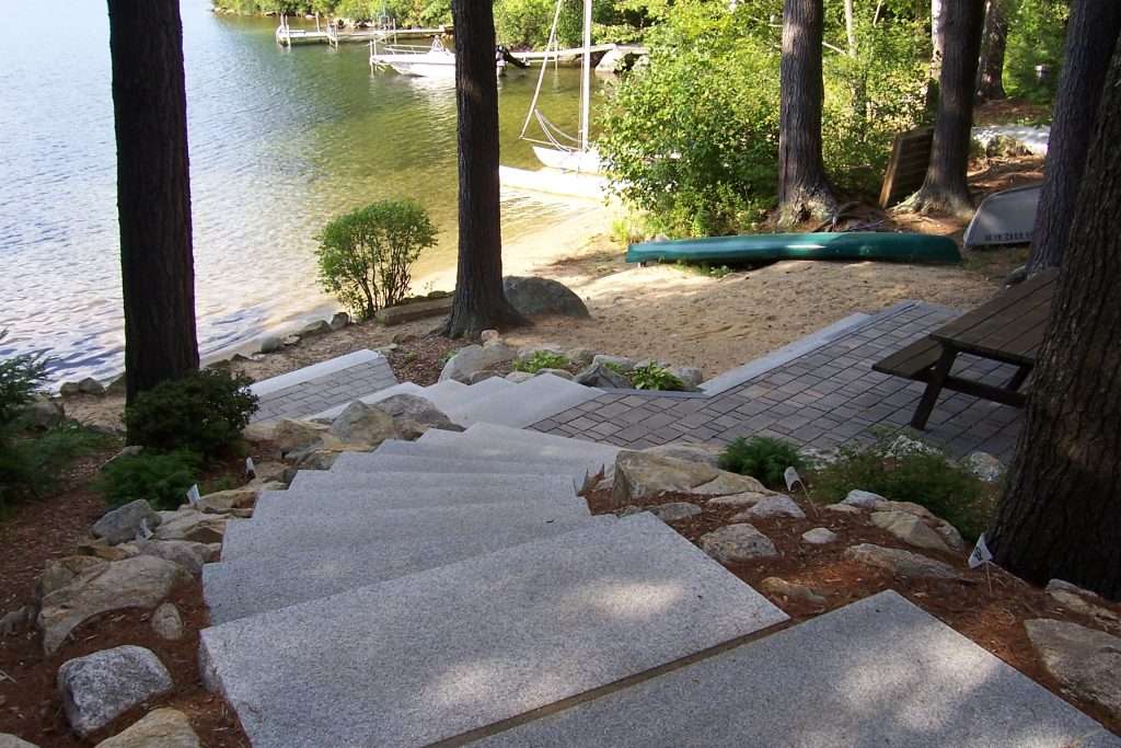 NH Lakeside Paver Patio with Granite Steps 3 Completed lakeside permeable paver patio with custom granite steps, shoreline landscaping, and waterfront outdoor living design by Landscapes by Tom in New Hampshire