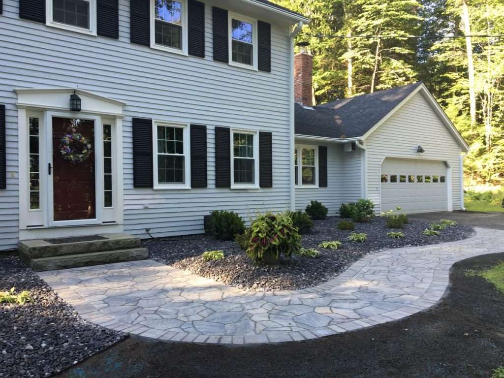 Completed front entry walkway installation with natural stone steps and professional landscape design by Landscapes by Tom in New Hampshire