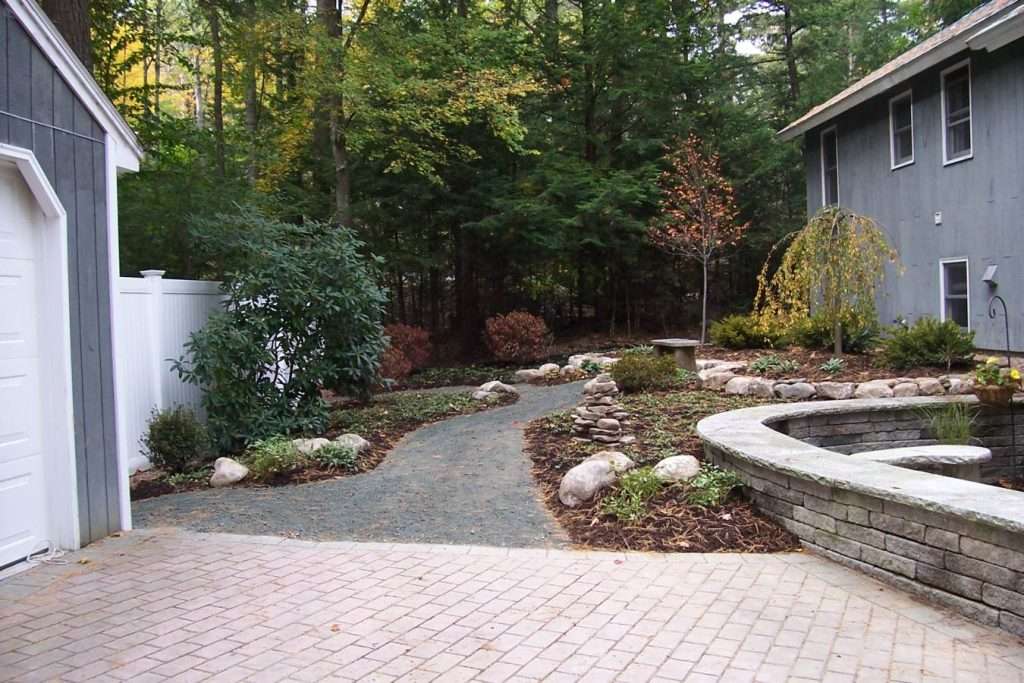 Completed courtyard pathway and landscape installation with natural stone walkway by Landscapes by Tom in New Hampshire