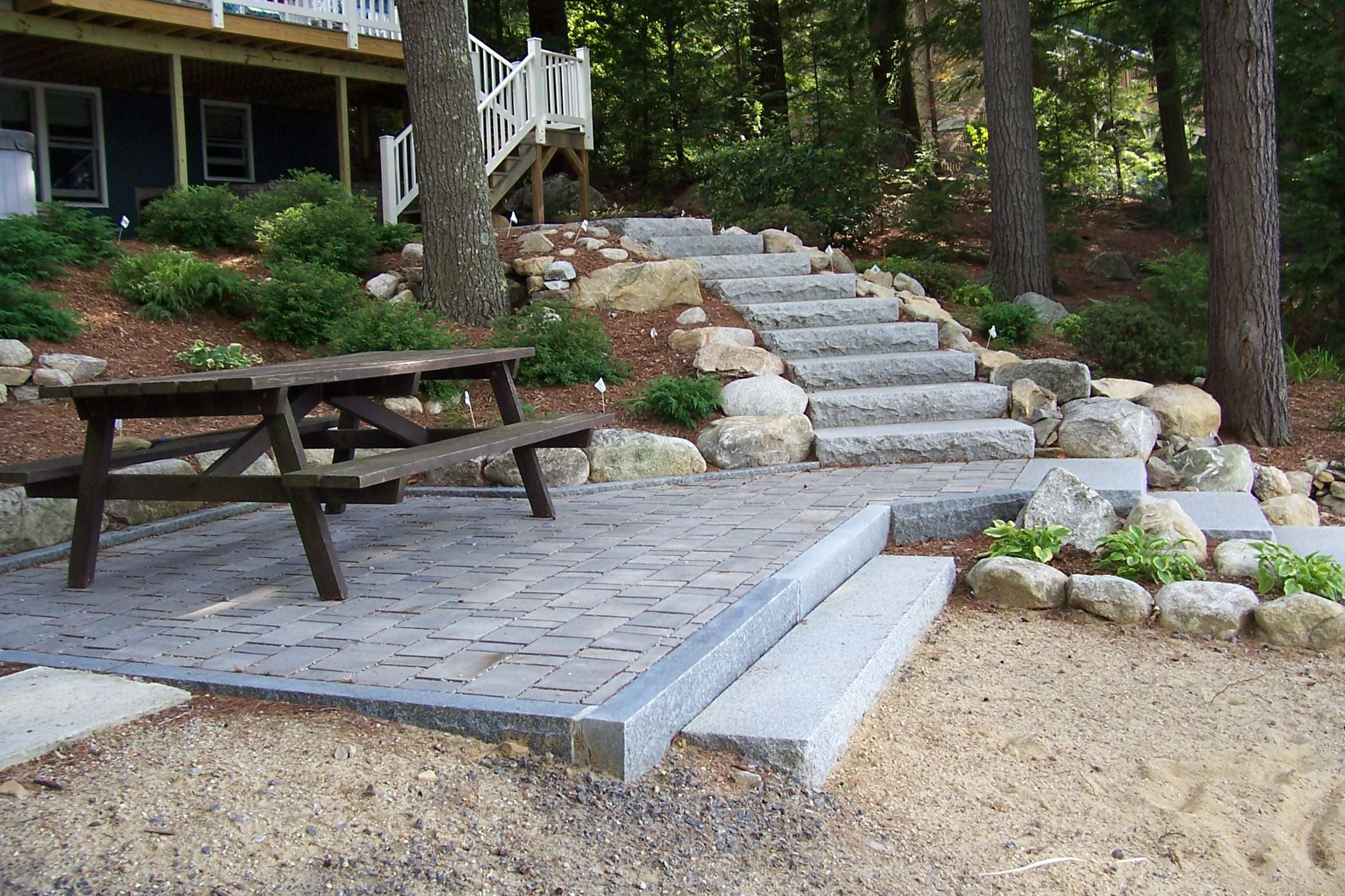 Custom patios and granite step installations featuring natural stone hardscaping, retaining walls, outdoor living design, and professionally crafted walkways for New Hampshire homes by Landscapes by Tom