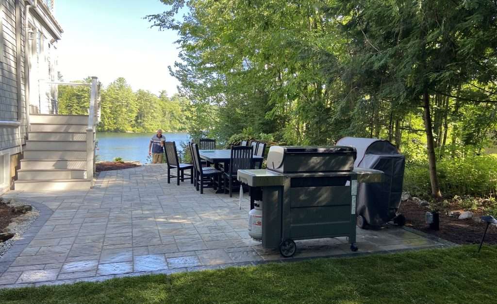 Landscaping Solutions for the Lakes Region 4 Spacious lakeside paver patio with outdoor dining area, grilling station, and waterfront views designed for entertaining, relaxation, and seamless backyard living